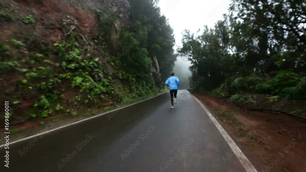Video of man running on country road. Fit young male is in sports clothing while jogging in nature. Full length rear view of man is representing his healthy lifestyle. Video of man running on country road. Fit young male is in sports clothing while jogging in nature. Full length rear view of man is representing his healthy lifestyle.