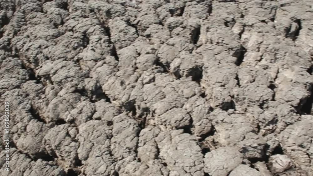 Gray cracked dried mud field in the crater of a mud volcano. Tracking right. Gray cracked dried mud field in the crater of a mud volcano. Tracking right.