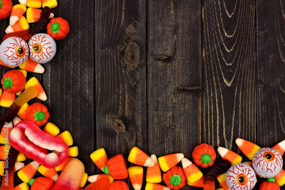 Halloween candy corner border over a dark black wood background