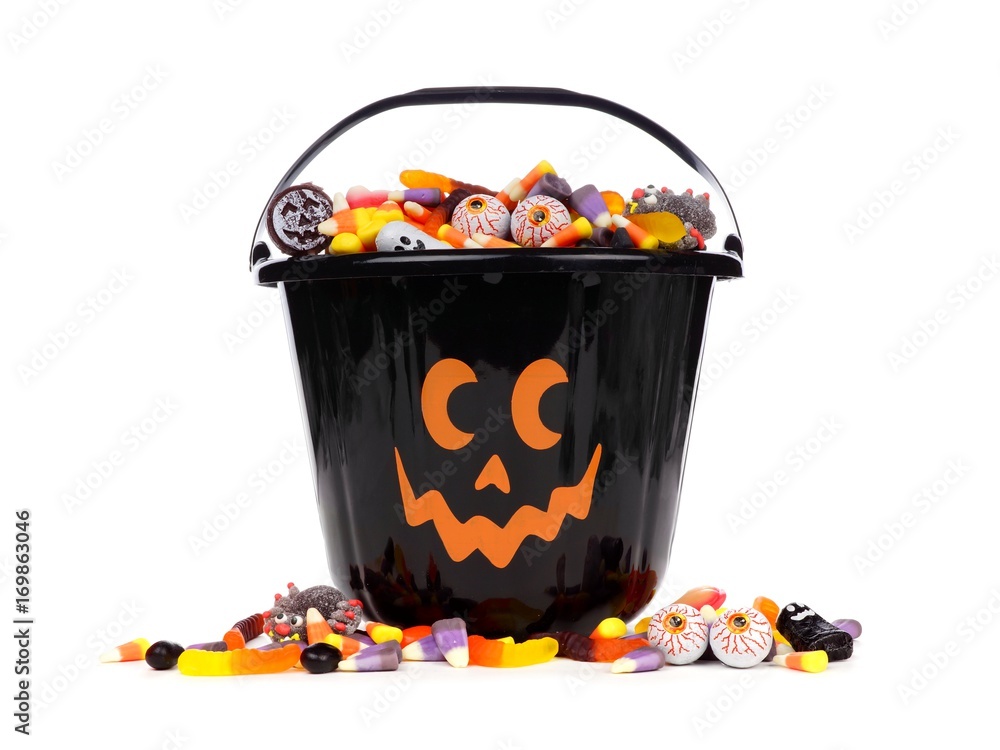 Fototapeta premium Black Halloween Jack o Lantern candy collector with scattered candy over a white background