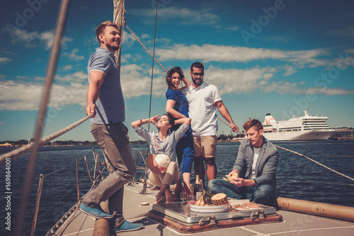 Happy friends eating fruits and drinking on a yacht