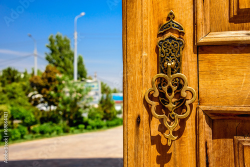 Golden carved handle of the wooden door at sunny summer day in Hazrat Imam Ensemble in the center of Tashkent city, Uzbekistan