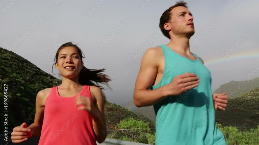 Running Fitness Sport People. Video of multiethnic couple jogging together. Fit man and woman are running against rainbow. They are representing their healthy lifestyle. Running Fitness Sport People. Video of multiethnic couple jogging together. Fit man and woman are running against rainbow. They are representing their healthy lifestyle.