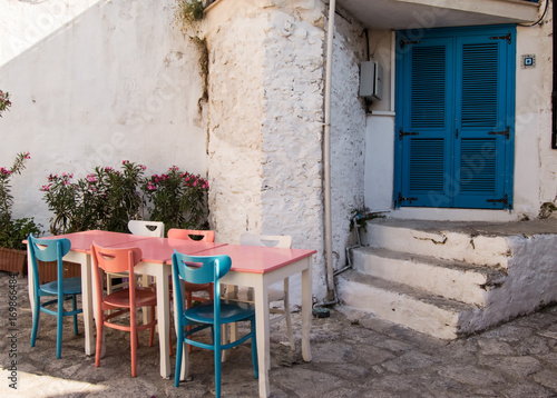 Old streets and houses of Marmaris. Table with colorful chairs  blue  pink  white  stands near entrance to the house with blue east Oriental input doors in old town of the resort of Marmaris in Turkey