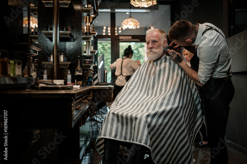 Senior man visiting hairstylist in barber shop. © Nejron Photo
