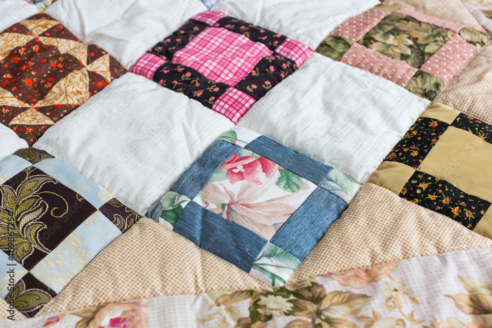 hobby, quilt, art concept. close up on piece quilt blanket patterned by a scattering of different geometrical figures such as triangles, squares and rhombuses hobby, quilt, art concept. close up on piece quilt blanket patterned by a scattering of different geometrical figures such as triangles, squares and rhombuses