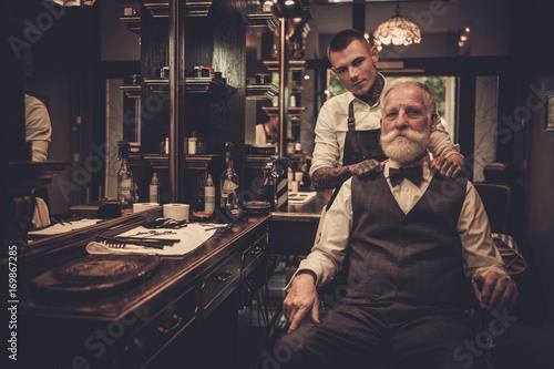 Senior man visiting hairstylist in barber shop. photo