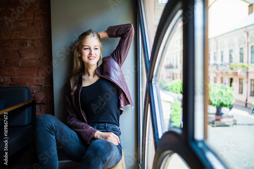 Young woman sitting on window sill in cafe photo