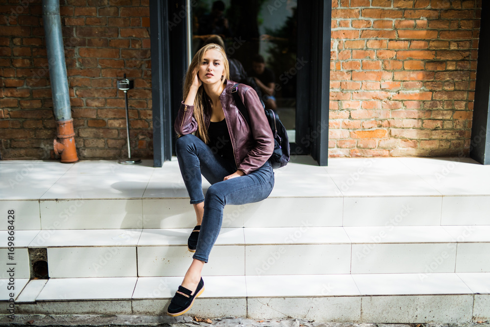 Casual style. Stylish woman in sunglasses sitting on the stone stairs. She  dressed in jacket, skinny jeans and shoes. Long hair, elegant, street  fashion Stock Photo | Adobe Stock
