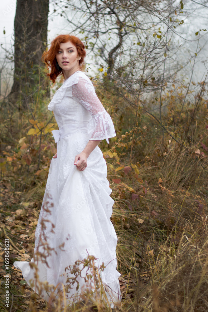 lady with red hair  in vintage white dress in forest