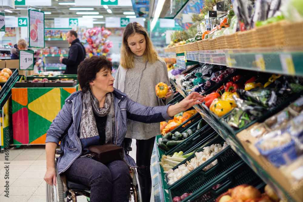 Girl helping disabled mothter in a grocery store.