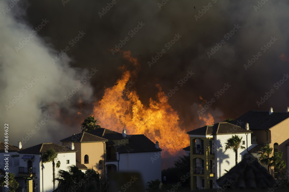 Wild fire close to houses being fought with airplanes and helicopters