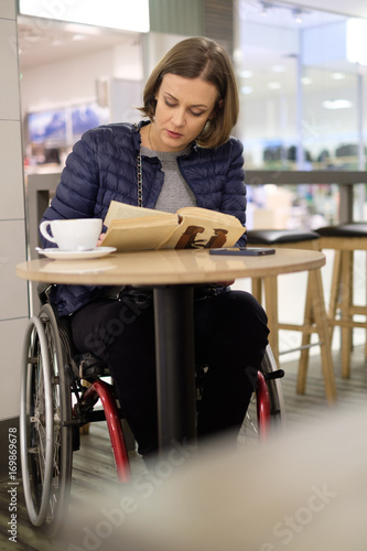 Physically challenged woman reading in a cafe