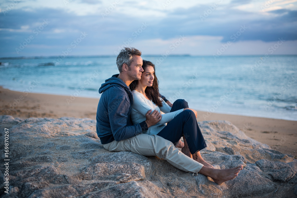 Fototapeta premium Beautiful couple sitting at the beach watching the sunset