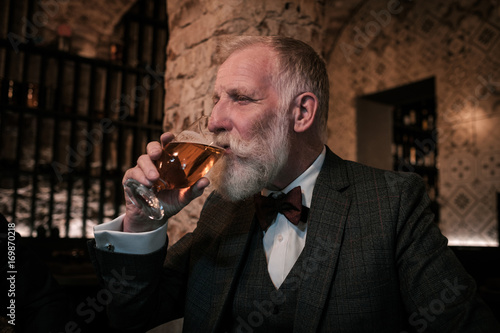 Fotografie Senior gentleman tasting craft beer