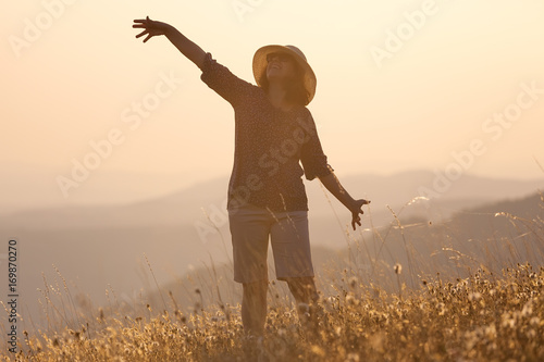 Tableau sur toile Girl posing on mountain and having fun on idyllic field at sunset