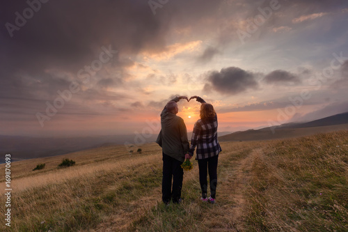 Senior couple in love on mountain at idyllic sunset
