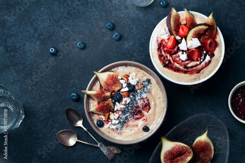 Blueberry banana smoothie bowl with figs and almond milk bowl with strawberries. Dark food phorography concept. Flatlay with copy space photo