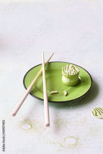 Upside Down Matcha Yuzu Macaron on green plate, on light background.