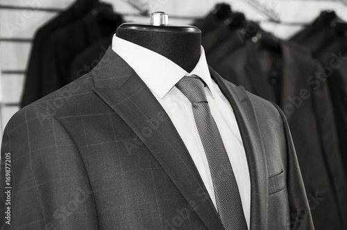 Man's suits: jackets, shirts, ties in a department store. Retro style. Men fashion industry. Nice clothes inside of a shop. Beautiful vintage. Black & White Photography. Old photo. Postcard