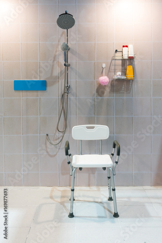 Padded shower chair with arms and back in bathroom with bright tile wall and floor.