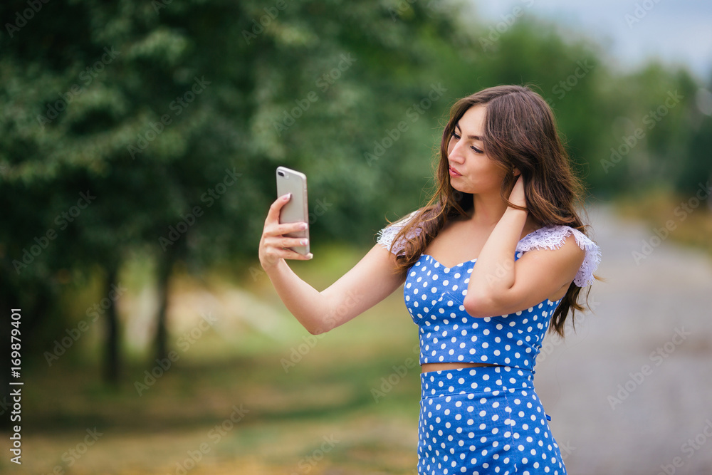 Young attractive woman taking selfie on smart phone in the park. Cropped image of young pretty girl walking in the street using mobile phone. Young attractive woman taking selfie on smart phone in the park. Cropped image of young pretty girl walking in the street using mobile phone.