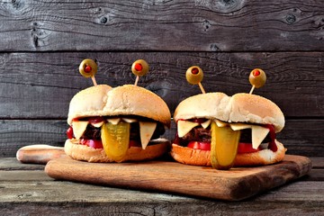 Halloween monster hamburgers on a paddle board against an old wood background