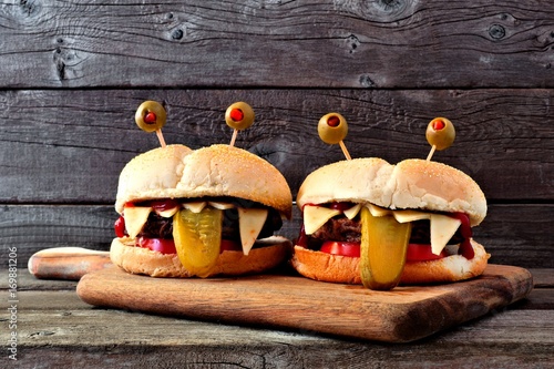 Halloween monster hamburgers on a paddle board against an old wood background