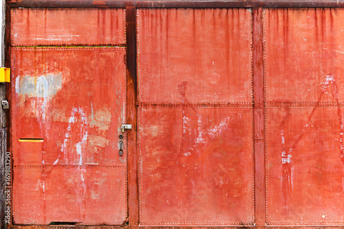Old rusty red steel front gate security door with three heavy metal padlocks
