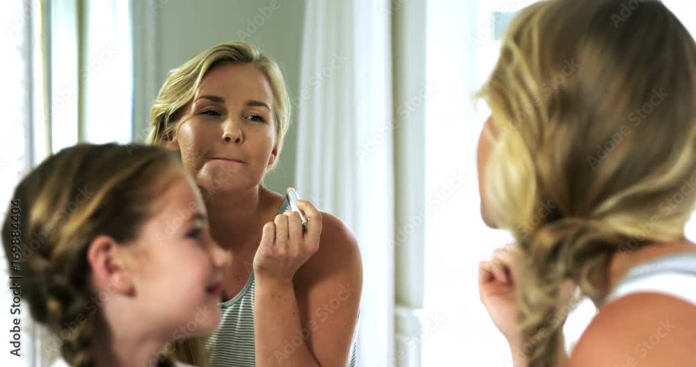 Mother and daughter applying lipstick in bedroom Mother and daughter applying lipstick in bedroom