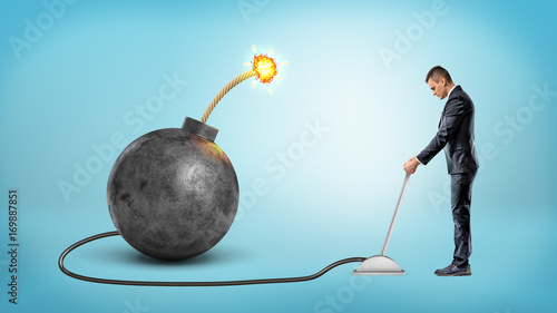 Konstfotografi A small businessman turning a metal lever connected to a large iron bomb with a lit fuse