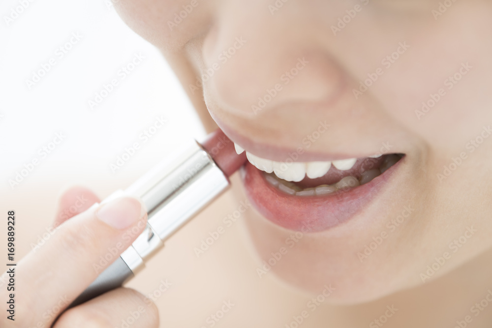 Naklejka premium A woman is using lipstick