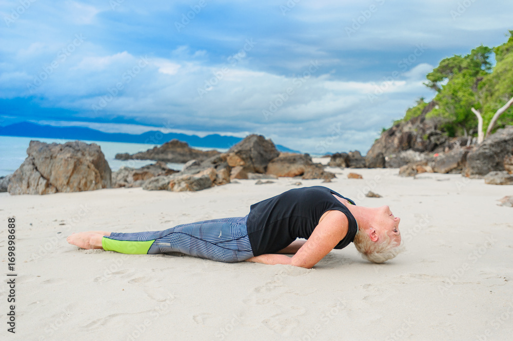 Beautiful mature aged woman doing yoga on a desert tropical beach Beautiful mature aged woman doing yoga on a desert tropical beach