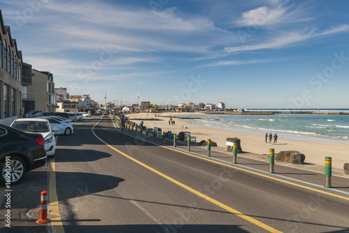 Beautiful scenery of coastal road alongside Woljeong Beach Jeju, South Korea with road-side shoplots. Awesome blue sky and ocean background. Selective focusing.