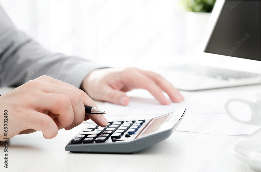 Accountant calculates tax. Working in the office with calculator Accountant calculates tax. Working in the office with calculator