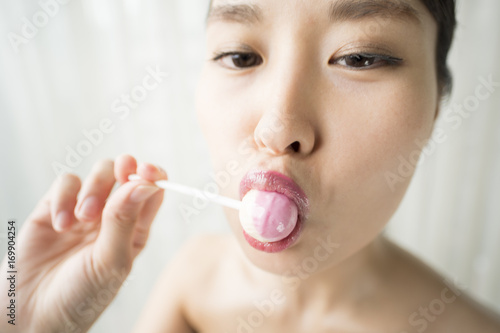 A woman licking a candy while staring