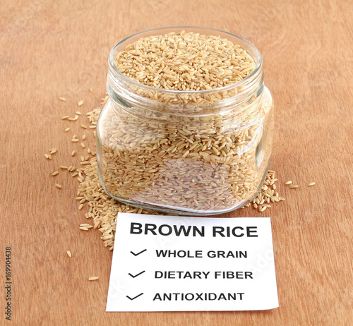 Brown rice, which is a whole grain and healthy food, in a bottle, with a note of some of its benefits.