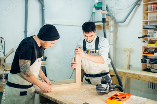 Man joining two parts of wooden planks. Worker carpenter joiner photo