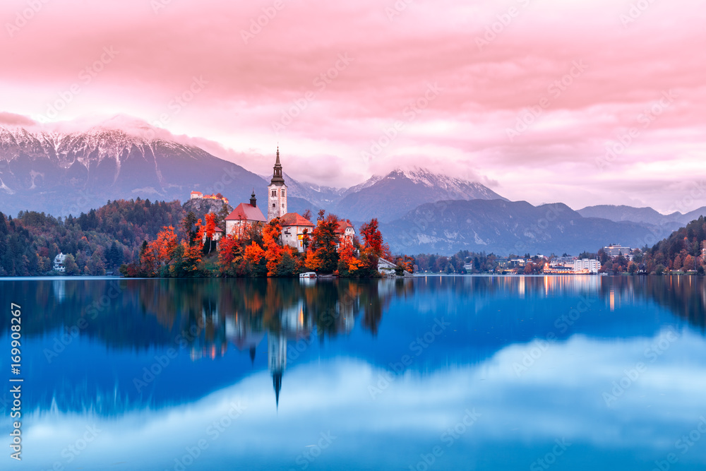 Obraz premium Bled lake in Slovenia, famous and very popular landmark and travel destination. Night scene of island with ancient church in the middle of Bled lake. Romantic place, sunset dusk scenery. Fall season.
