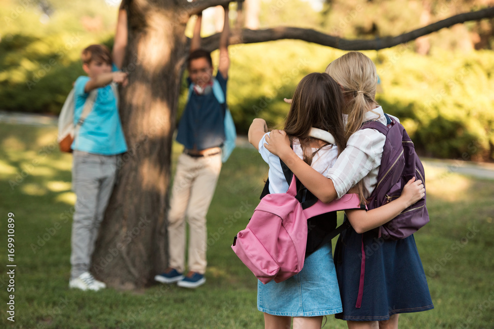 schoolgirls with backpacks in park