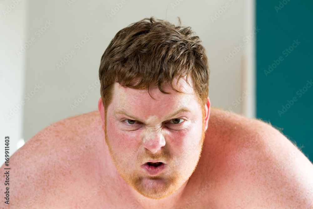 Obraz premium Rothaariger junger dicker Mann schreit wütend und zerreißt sein Shirt