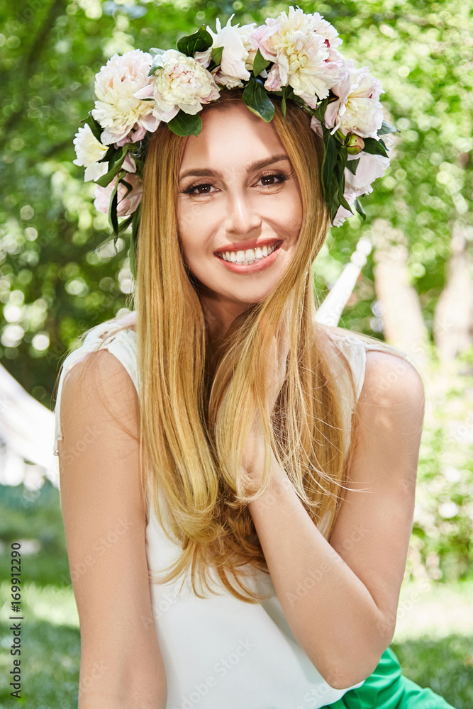 Fototapeta premium Portrait of beautiful sexy blond woman happy life style smile, weekend out for a walk in a picnic yard in the summer garden, model warm summer weather flowers in her hair.