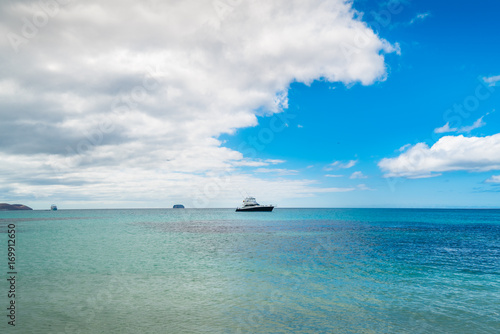 Beautiful Blue Ocean, Galapagos. Waves on the Beach with Blue Sky Background. Tropical Nature Landscape. Tropical Paradise Isolated Island. Clean Blue Ocean View. Nobody Sea Tropical Pattern. Boat
