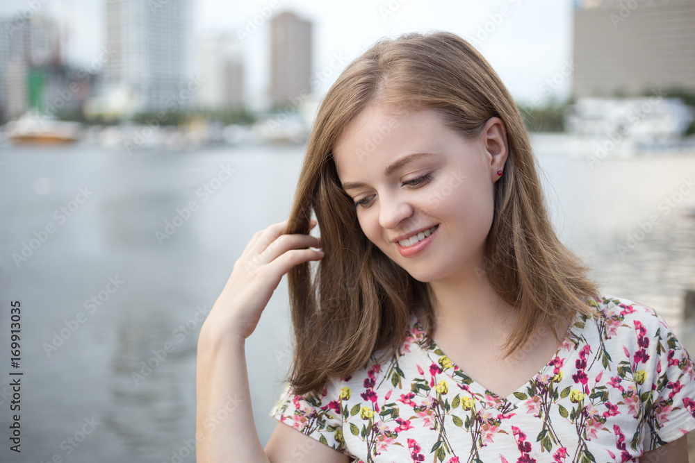 Portrait of young smiling caucasian woman, with embankment area at background  
