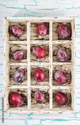 Plums in a wooden box with cells