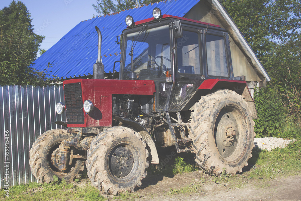 Obraz premium old red tractor near the house