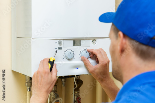 worker set up central gas heating boiler at home photo