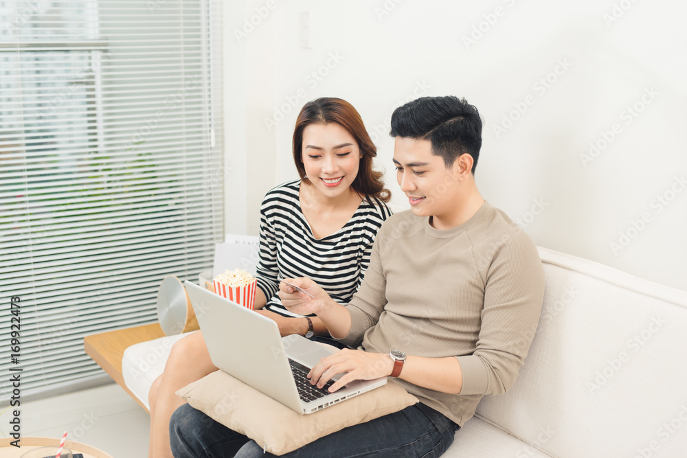 Young asian couple payment online using laptop buying movie ticket Young asian couple payment online using laptop buying movie ticket