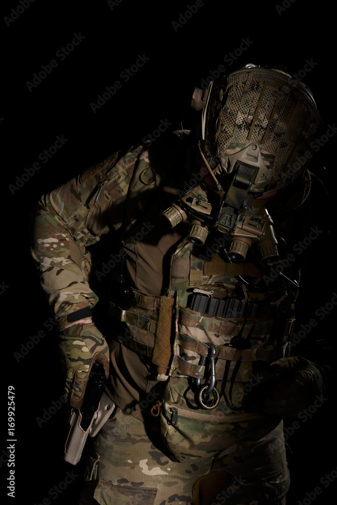 Soldier in military uniform reaching for pistol on background of dark wall 24