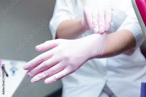 A young female doctor preparing herself for working  putting on protective gloves.